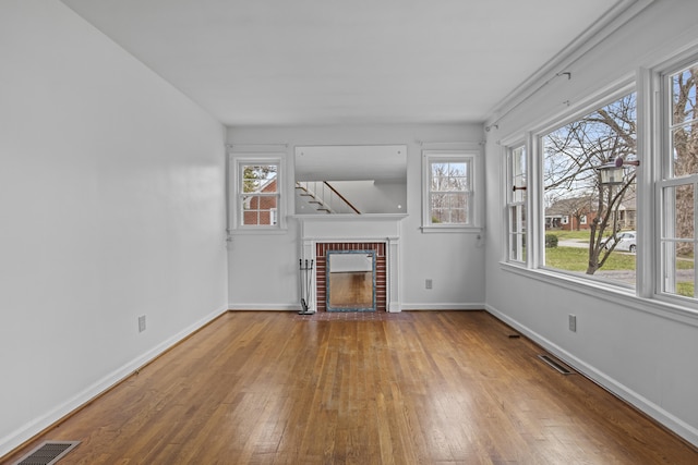 unfurnished living room featuring wood-type flooring, baseboards, and visible vents