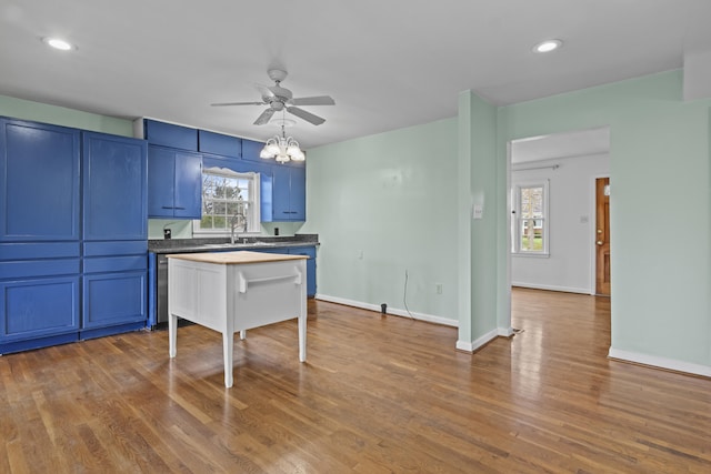 kitchen featuring baseboards, blue cabinetry, a sink, ceiling fan with notable chandelier, and dark wood-style floors