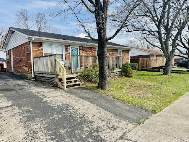 ranch-style house with aphalt driveway, brick siding, a front lawn, and a wooden deck
