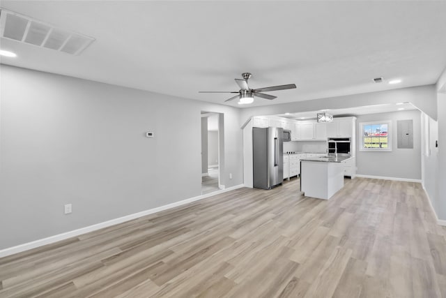 unfurnished living room with baseboards, electric panel, a ceiling fan, light wood-style floors, and visible vents