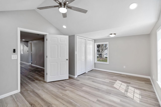 unfurnished bedroom with a closet, baseboards, a ceiling fan, lofted ceiling, and light wood finished floors