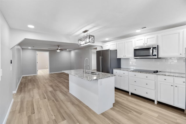 kitchen with tasteful backsplash, white cabinetry, a ceiling fan, appliances with stainless steel finishes, and a sink