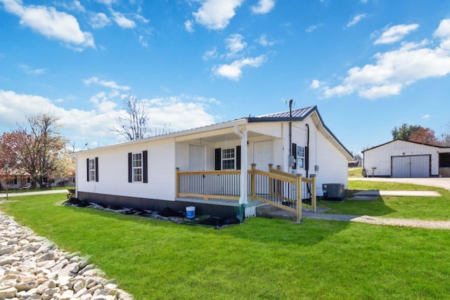 view of front of home with an outbuilding, covered porch, a detached garage, and a front lawn