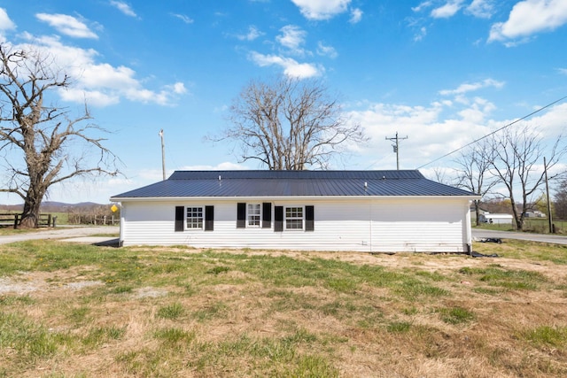 back of property with metal roof and a lawn