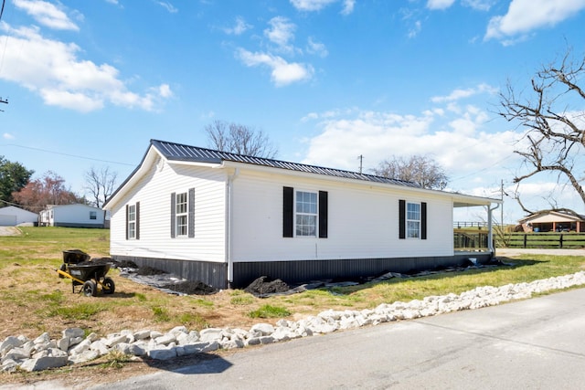 view of property exterior with metal roof and fence