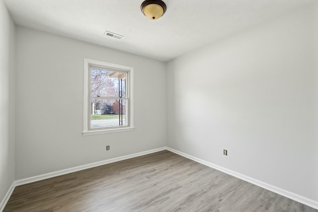 spare room featuring baseboards, visible vents, and wood finished floors