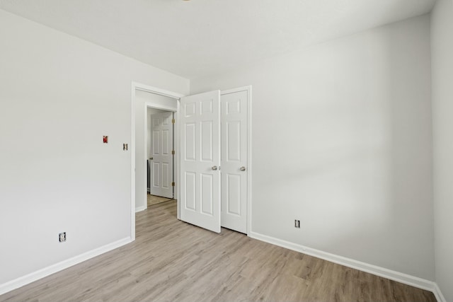 empty room featuring baseboards and light wood finished floors