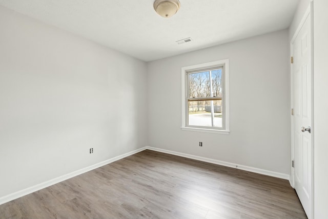 empty room featuring baseboards, visible vents, and wood finished floors