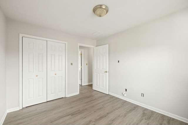 unfurnished bedroom with light wood finished floors, baseboards, and a closet