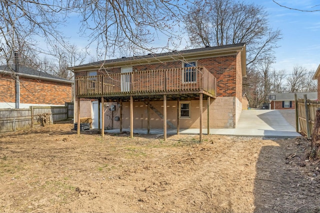 back of property with a patio, brick siding, a wooden deck, and fence private yard
