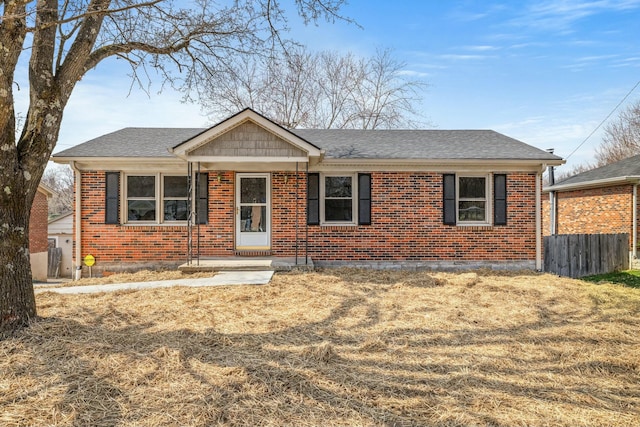 single story home featuring brick siding, fence, and roof with shingles