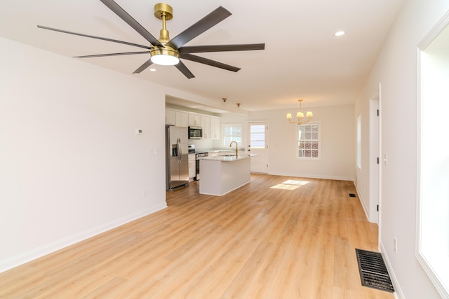 948 Meadow Ln, Lexington, KY 40505 - unfurnished living room featuring light wood-type flooring, ceiling fan with notable chandelier, baseboards, a sink, and visible vents