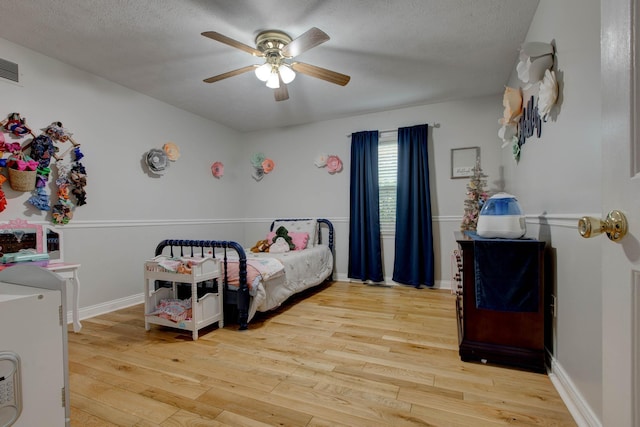 bedroom with baseboards, a textured ceiling, and light wood-type flooring