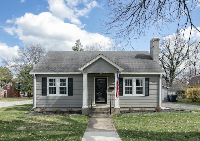 bungalow-style house featuring a chimney, a shingled roof, and a front lawn