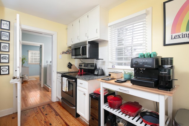 kitchen featuring white cabinets, stainless steel appliances, tasteful backsplash, and light wood finished floors