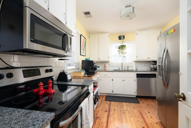 kitchen with a sink, white cabinetry, appliances with stainless steel finishes, visible vents, and light wood-style floors