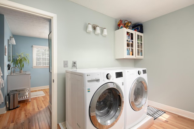 washroom with laundry area, a sink, light wood-style floors, and separate washer and dryer