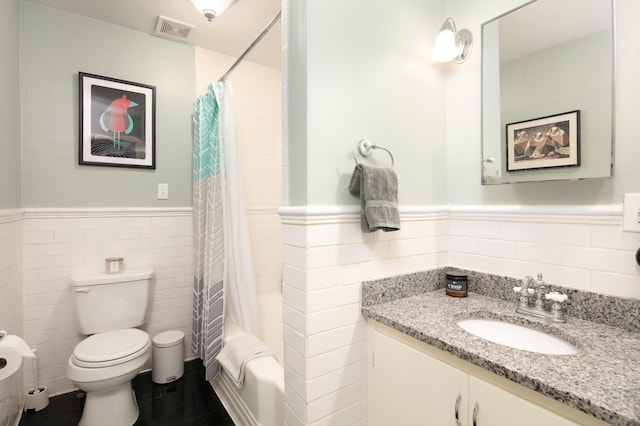 bathroom featuring a wainscoted wall, visible vents, and tile walls
