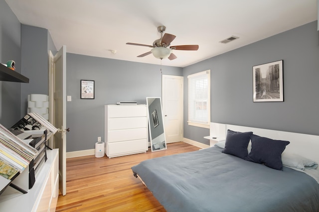 bedroom with a ceiling fan, baseboards, light wood finished floors, and visible vents