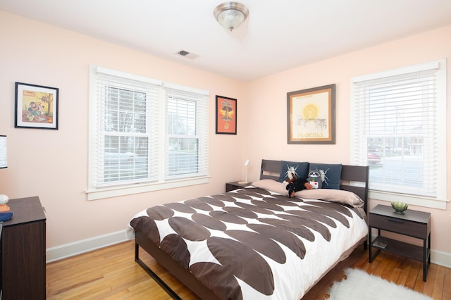 bedroom featuring baseboards, visible vents, and wood finished floors