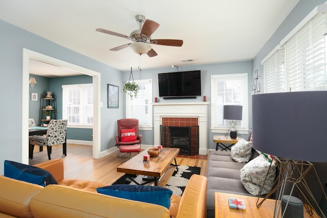 living room featuring visible vents, baseboards, a fireplace, wood finished floors, and ceiling fan