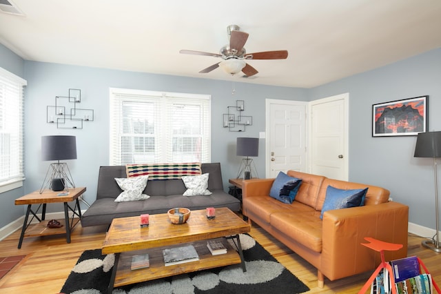living area with light wood-type flooring, a ceiling fan, baseboards, and visible vents