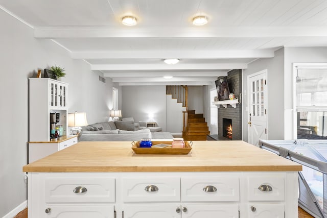 29 Quails Run Ln, West Liberty, KY 41472 - kitchen featuring open floor plan, wood counters, a fireplace, beamed ceiling, and white cabinetry