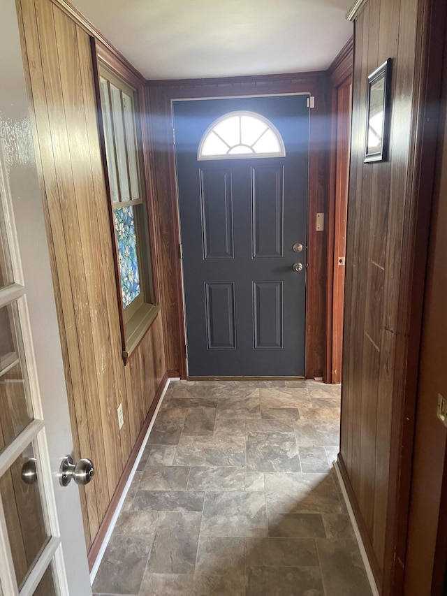 doorway to outside featuring stone finish flooring and wooden walls