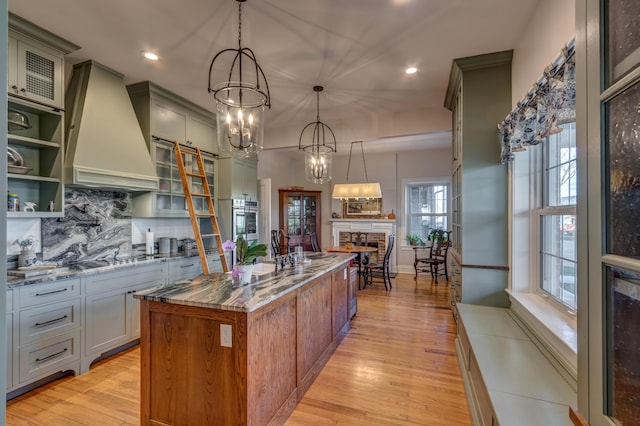 443 Hutchison Rd, Paris, KY 40361 - kitchen featuring a center island with sink, stovetop, custom exhaust hood, and light stone countertops