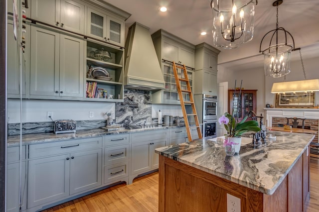 443 Hutchison Rd, Paris, KY 40361 - kitchen with stainless steel double oven, premium range hood, black electric stovetop, light stone counters, and a notable chandelier