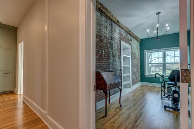 443 Hutchison Rd, Paris, KY 40361 - interior space featuring baseboards, built in shelves, wood finished floors, brick wall, and an inviting chandelier