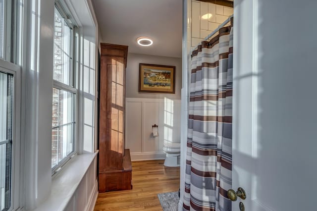 443 Hutchison Rd, Paris, KY 40361 - bathroom with toilet, a shower with curtain, wood finished floors, wainscoting, and a decorative wall