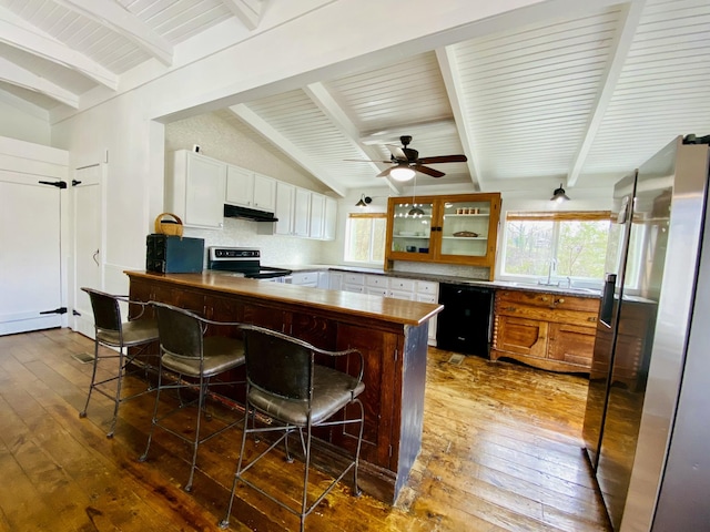 kitchen with a peninsula, dark wood-type flooring, under cabinet range hood, black appliances, and backsplash