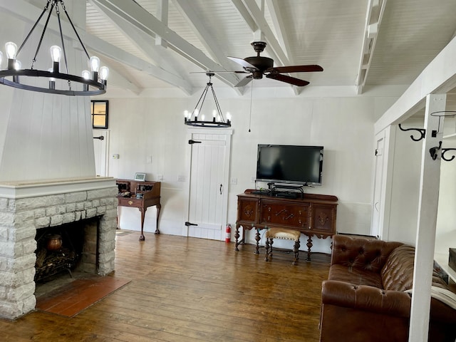 living room featuring hardwood / wood-style floors, a stone fireplace, ceiling fan with notable chandelier, and vaulted ceiling with beams