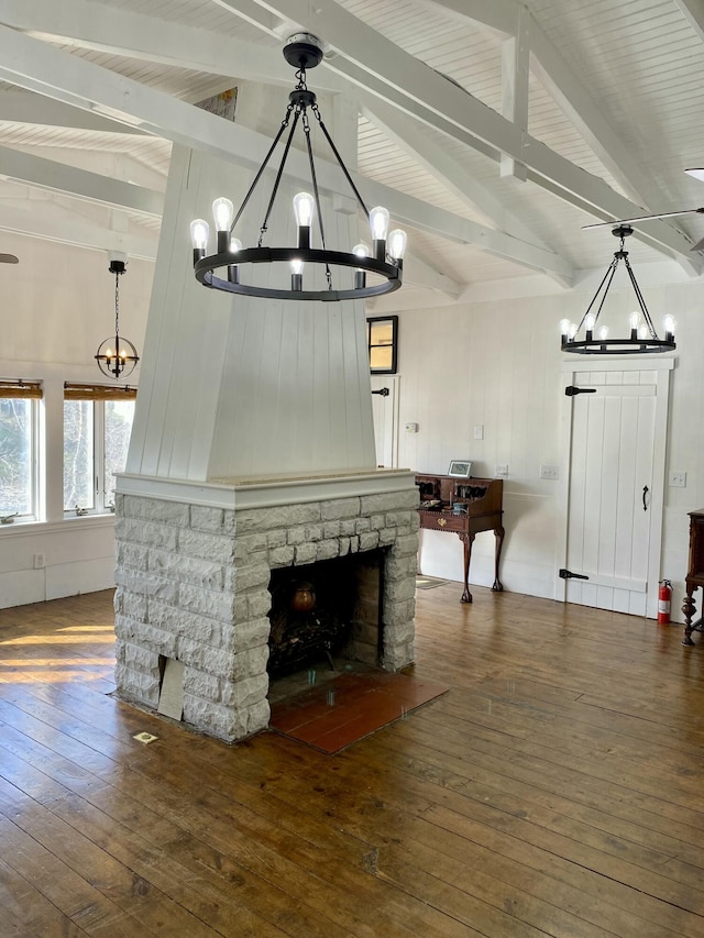 unfurnished living room featuring an inviting chandelier, hardwood / wood-style floors, vaulted ceiling with beams, and a fireplace