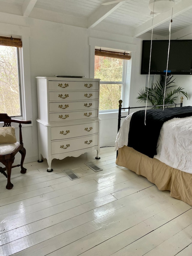 bedroom with beamed ceiling, visible vents, and light wood-style flooring