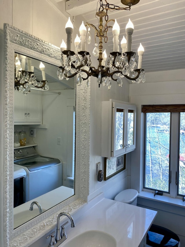 bathroom with vanity, washing machine and dryer, and a notable chandelier