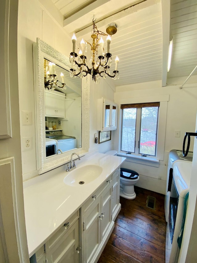 bathroom featuring independent washer and dryer, hardwood / wood-style flooring, beam ceiling, and a chandelier