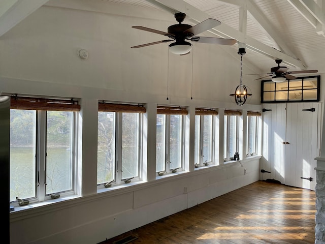 unfurnished sunroom featuring visible vents, high vaulted ceiling, beamed ceiling, and wood finished floors
