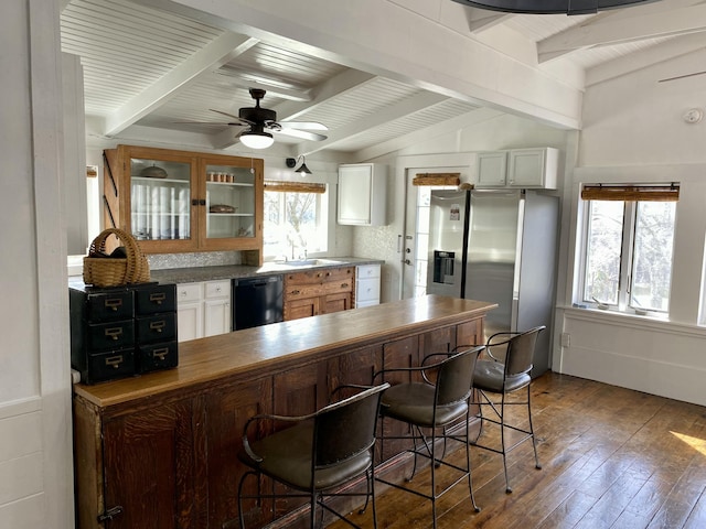 kitchen featuring vaulted ceiling with beams, a breakfast bar, dishwasher, dark wood finished floors, and glass insert cabinets