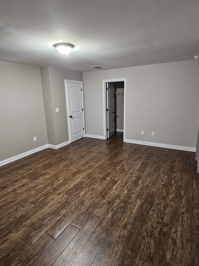 empty room with baseboards, dark wood-style floors, and visible vents