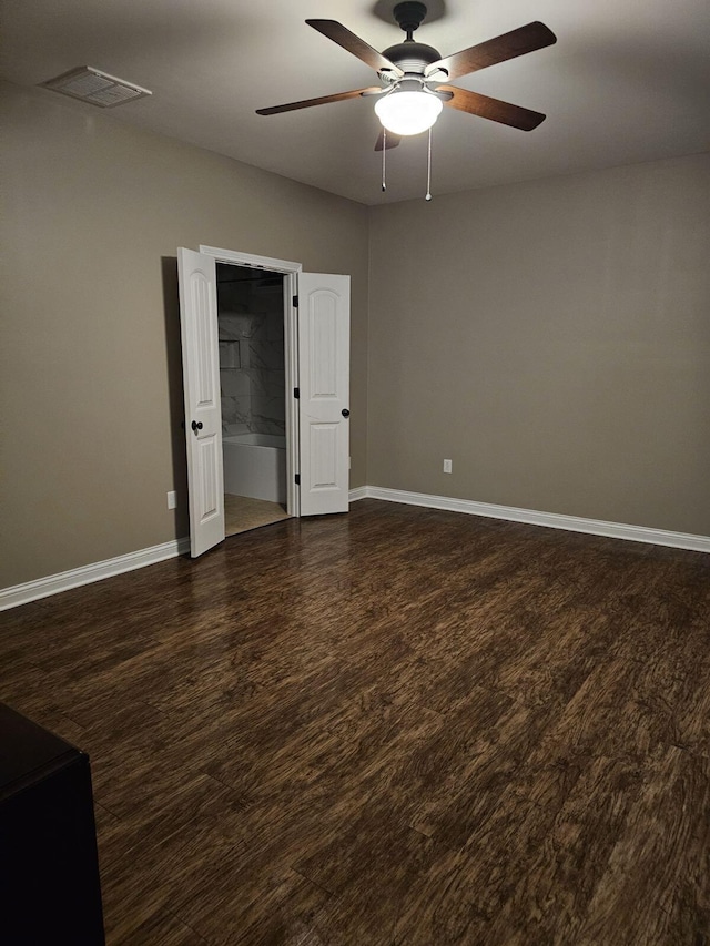 empty room with baseboards, a ceiling fan, wood finished floors, and visible vents