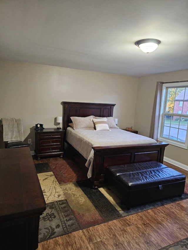 bedroom with baseboards and dark wood-type flooring