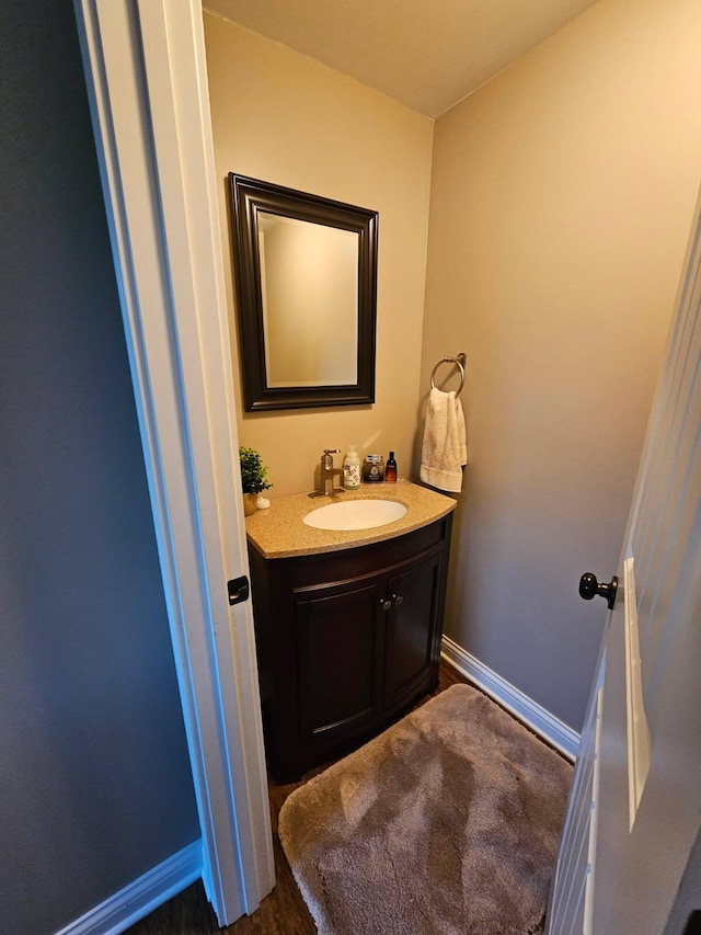 bathroom featuring vanity, baseboards, and wood finished floors