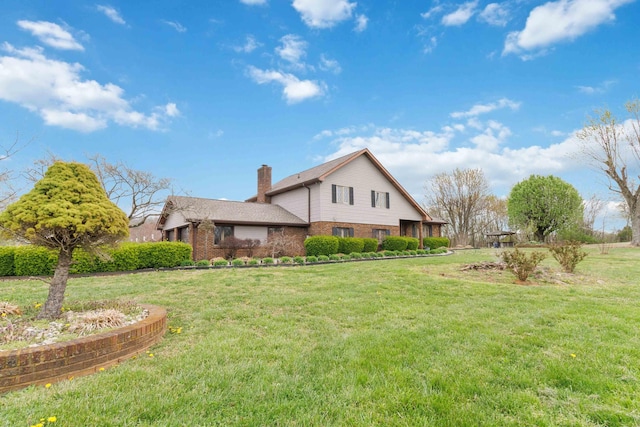 back of house with brick siding, a yard, and a chimney