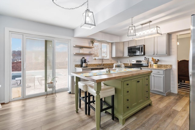 kitchen featuring green cabinetry, light wood-style flooring, butcher block countertops, and stainless steel appliances