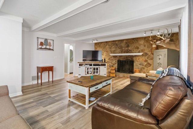 living room featuring a fireplace, wood finished floors, baseboards, beamed ceiling, and arched walkways