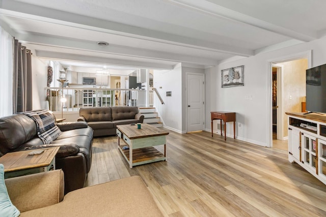 living area with baseboards, light wood-style flooring, stairway, and beamed ceiling