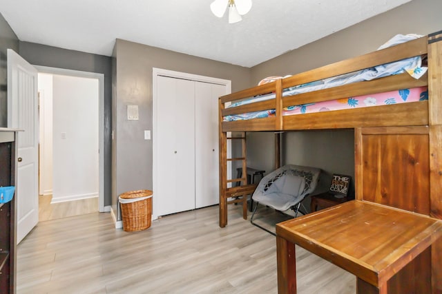 bedroom featuring a closet, baseboards, and light wood finished floors