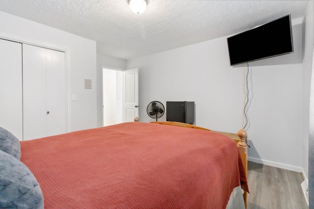 bedroom featuring a closet, baseboards, a textured ceiling, and wood finished floors